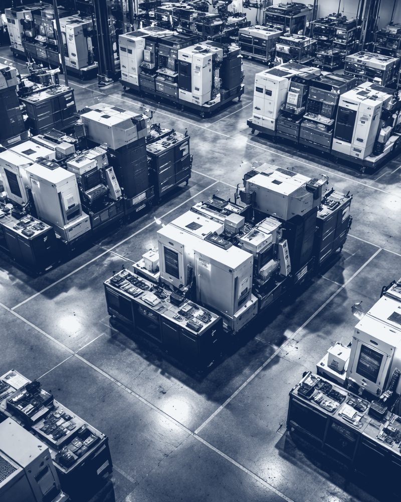 An aerial view of a factory floor of machining equipment, in navy tones.