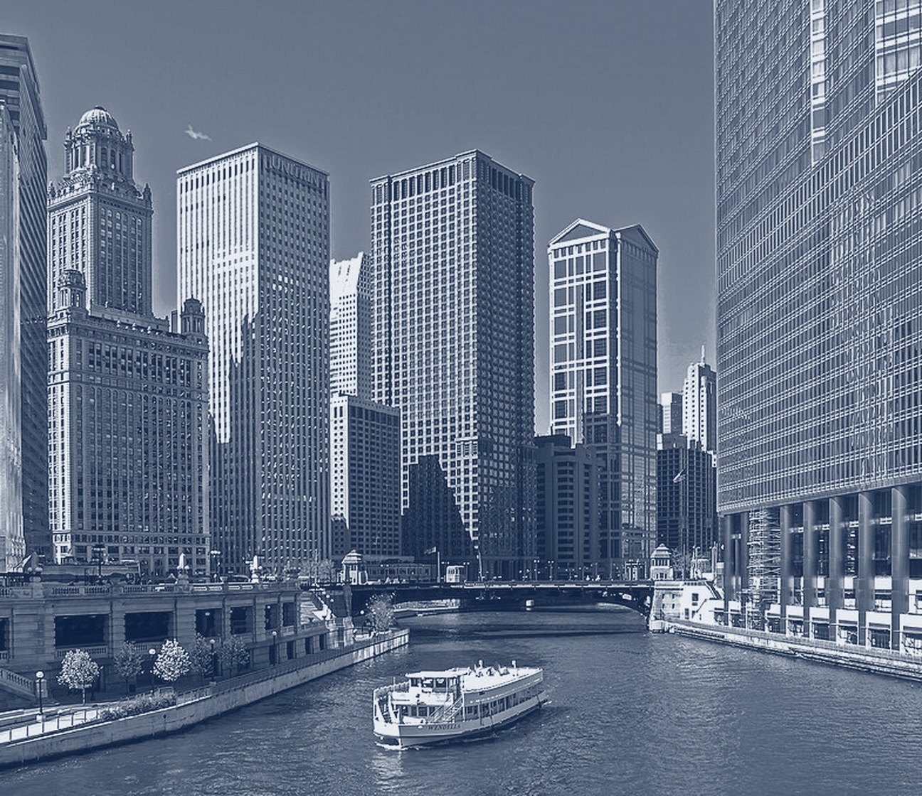 Skyscrapers along the Chicago River, with a tour boat in the channel.