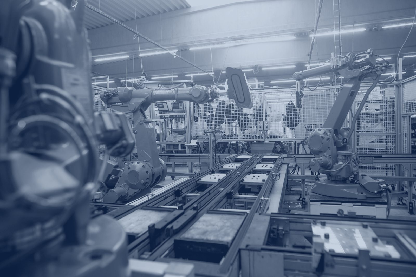 Robotic arms on an automated production line, shown in navy tones.