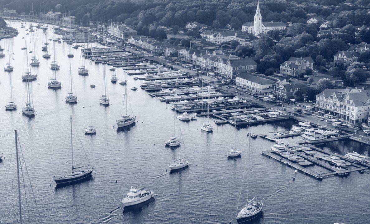A harbor full of moored sailboats seen from above, in navy tones.