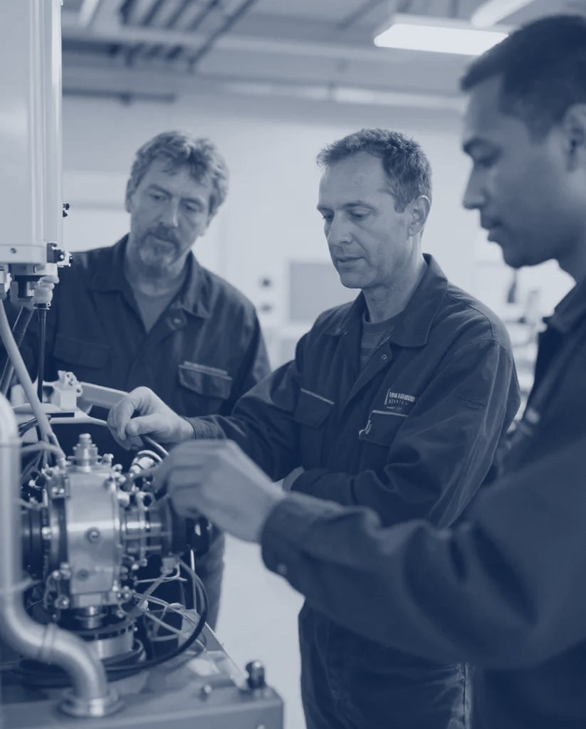 A field service technician at work on industrial equipment, shown in navy tones