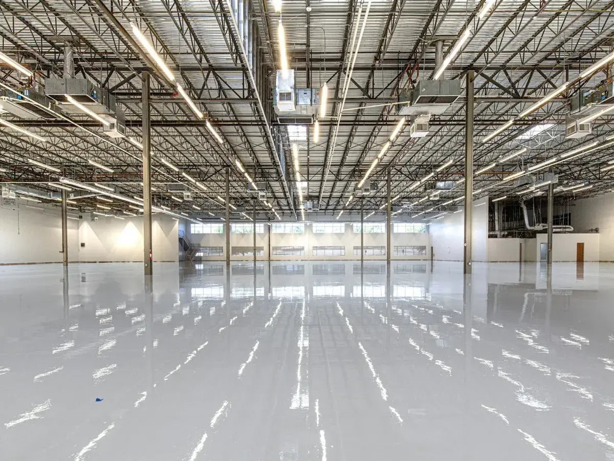 The interior of a large U.S. industrial facility, structural bays and open floor, in navy duotone